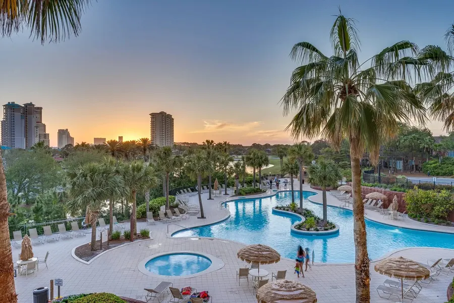 Resort lagoon pool with palm trees and hot tub at sunset