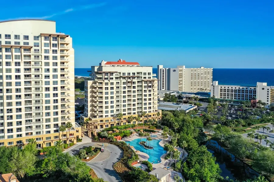 Aerial photo of beachfront resort towers and lagoon pool under blue skies