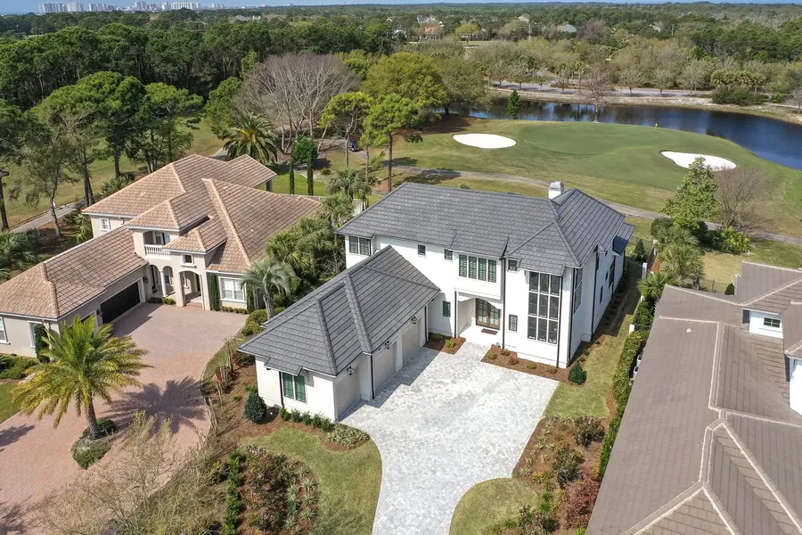 Aerial view of a luxury golf course home with paver driveway