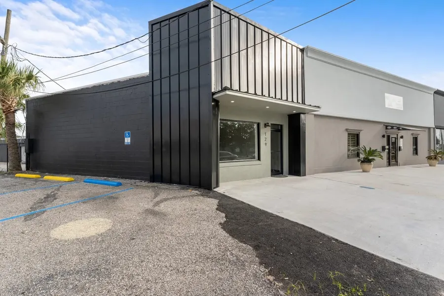 Modern black and gray commercial storefront with metal-panel facade and parking lot