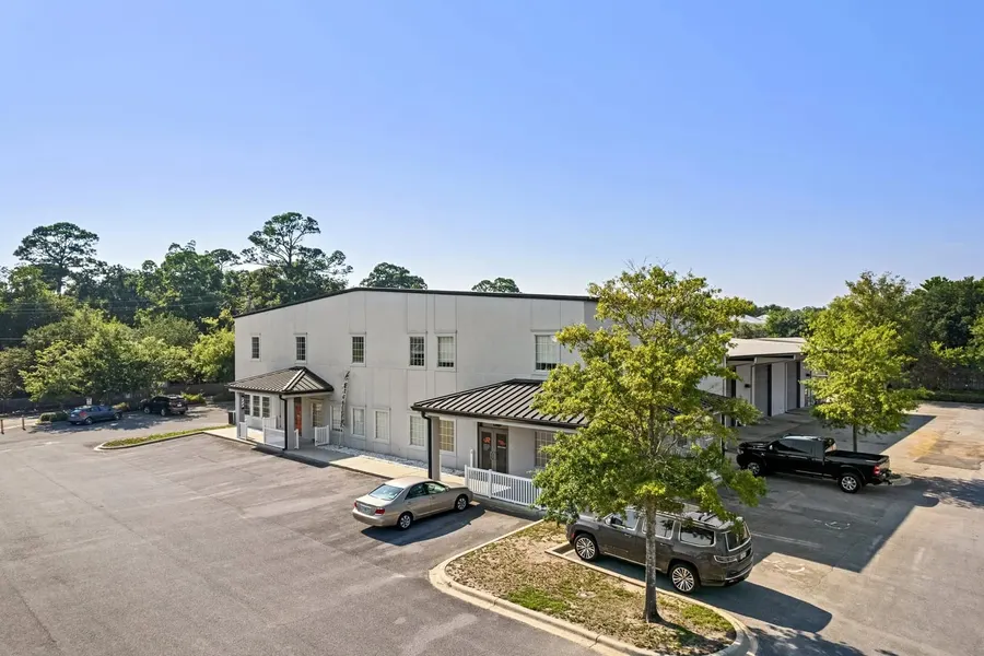 Aerial view of a two-story white office building with covered entrances and parking