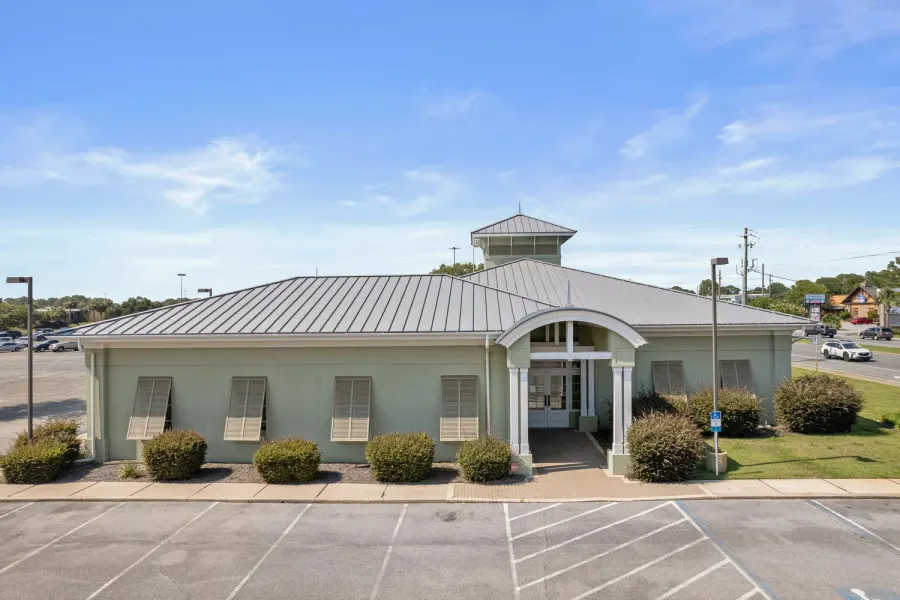 Elevated view of a green bank-style building with metal roof and cupola in Destin