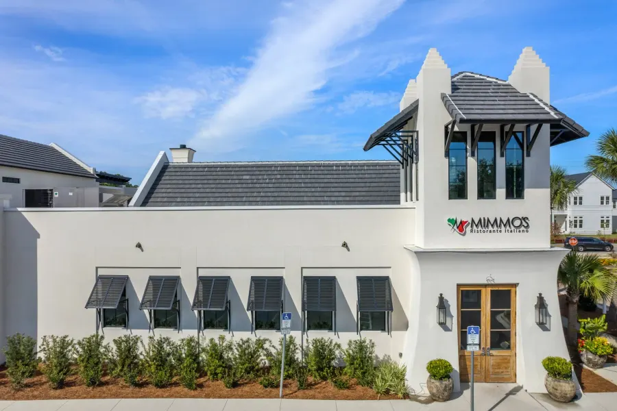 White Italian restaurant exterior with tower entrance and bahama shutters under blue Florida sky