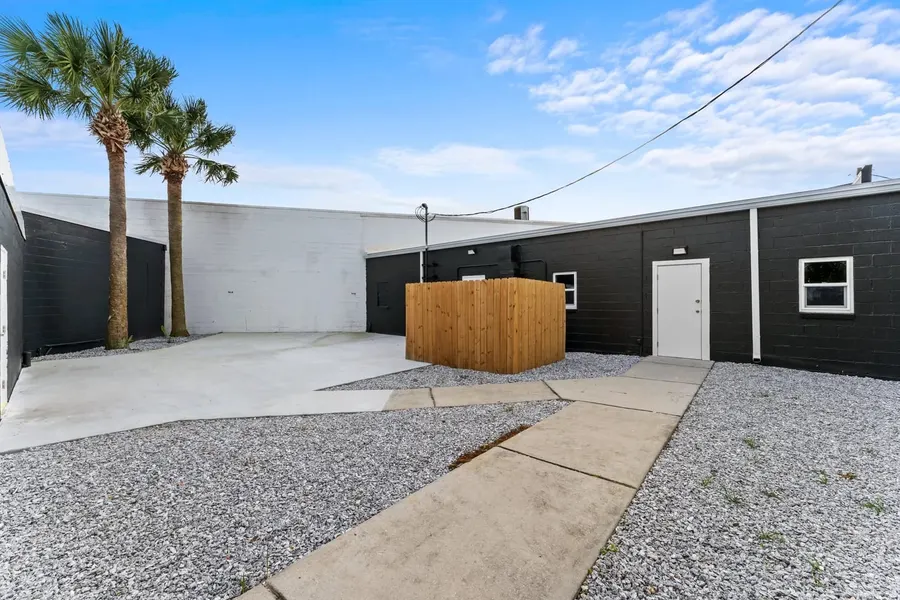 Rear courtyard of commercial building with palm trees and wood privacy enclosure