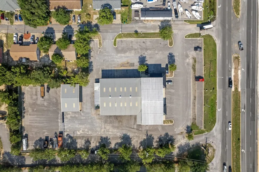 Overhead aerial of a metal warehouse building, parking areas, and highway frontage
