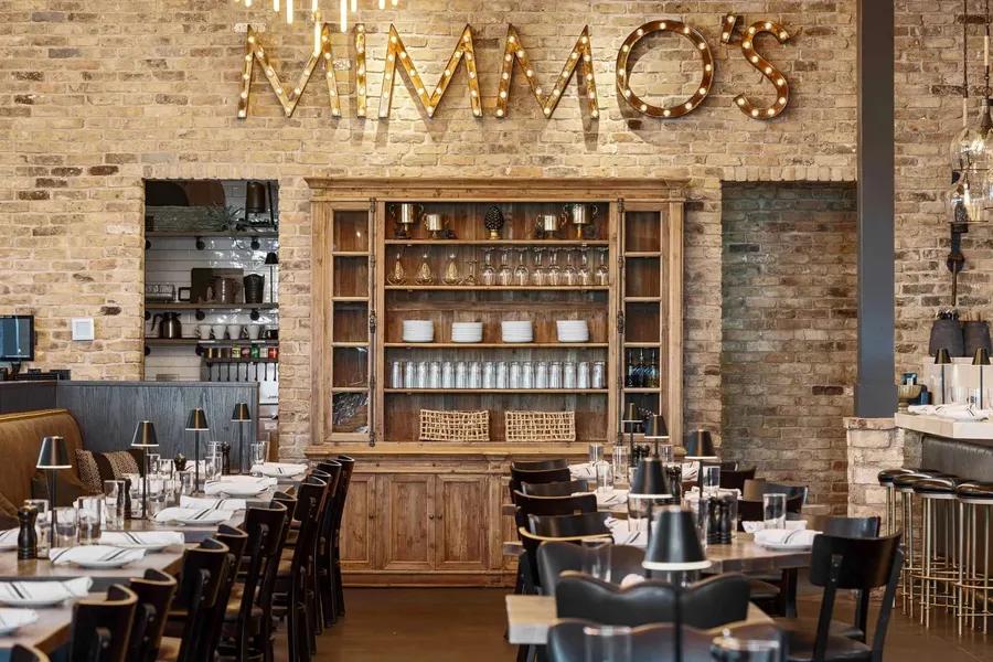 Restaurant dining room with brick walls, marquee sign, and wooden display hutch