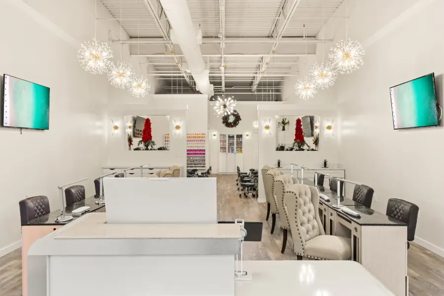 Bright white nail salon interior with sparkling chandeliers and manicure stations