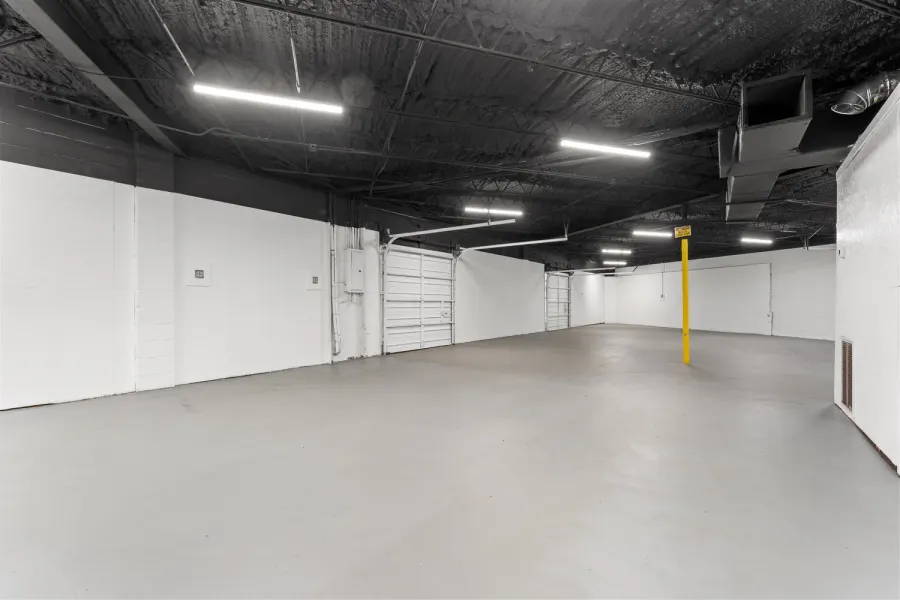 Empty warehouse interior with white walls, epoxy floor, and roll-up door