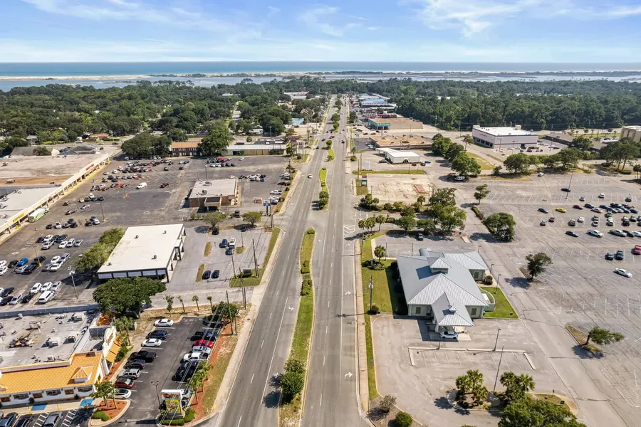 High aerial of a coastal Florida commercial corridor with the gulf beyond