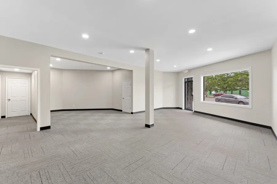 Open carpeted commercial suite with recessed lighting and street-facing window