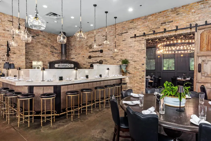 Brick-walled restaurant interior with marble bar and brass stools