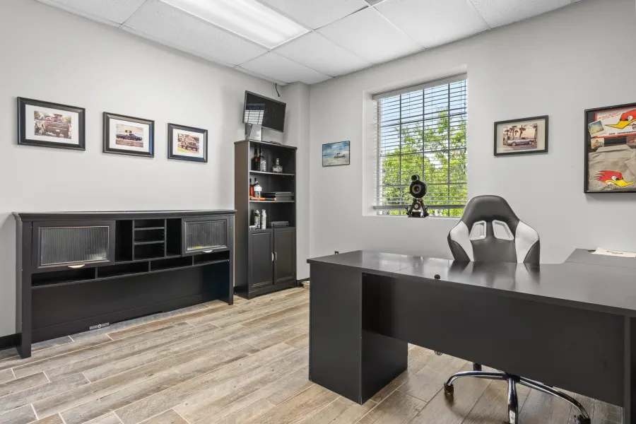 Private office with black desk, shelving, and automotive artwork
