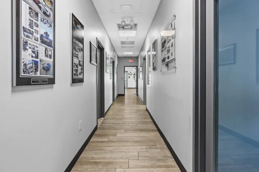 Office hallway lined with framed automotive magazine features and wood-look flooring