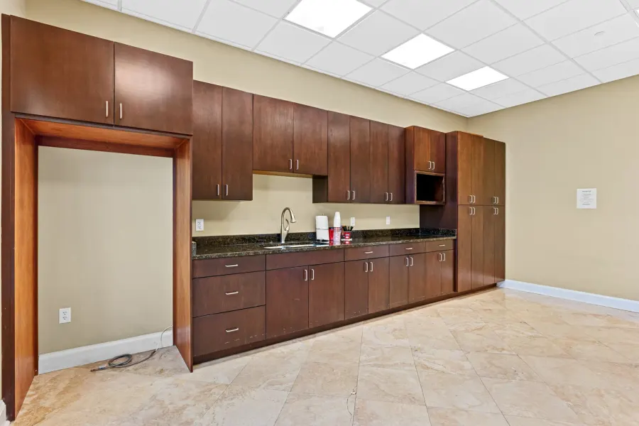 Commercial break room with dark wood cabinetry and granite counters