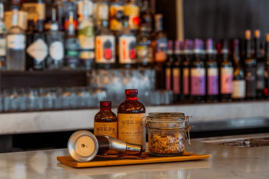 Craft cocktail bar detail with bitters bottles and jigger on marble counter