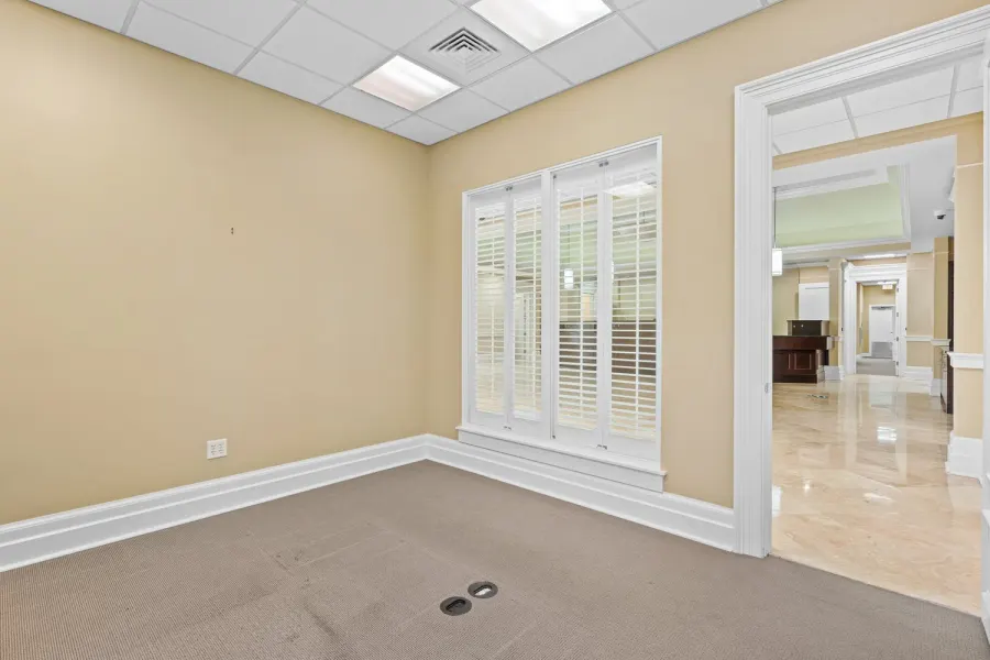 Empty office suite with plantation shutters opening to a marble hallway