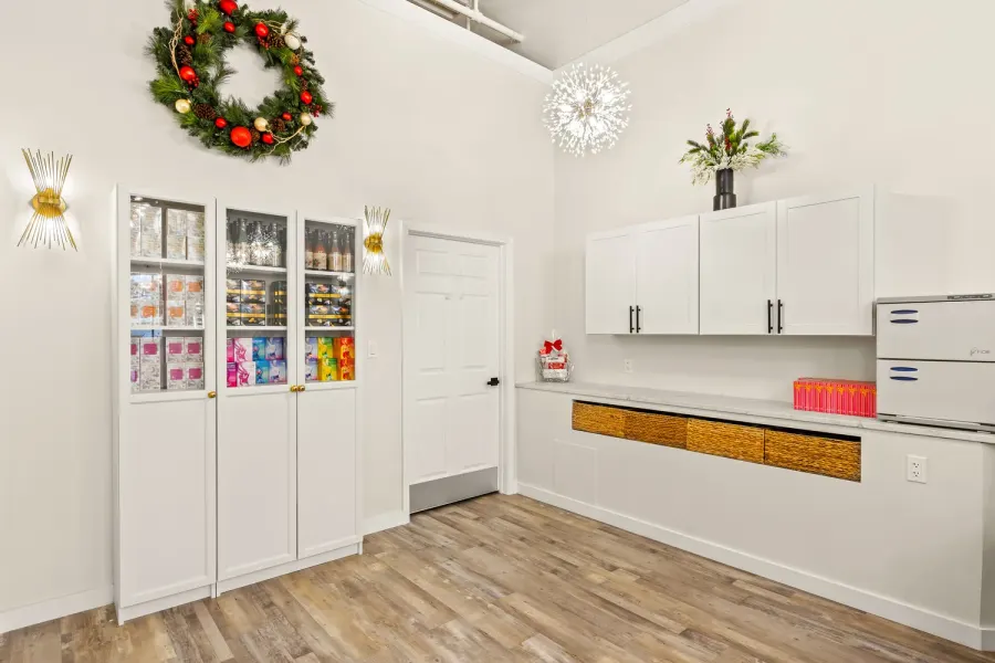 Bright white boutique interior with display cabinets and holiday wreath