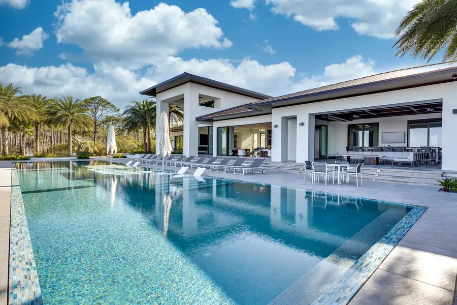 Modern estate with resort-style pool, loungers, and outdoor living area