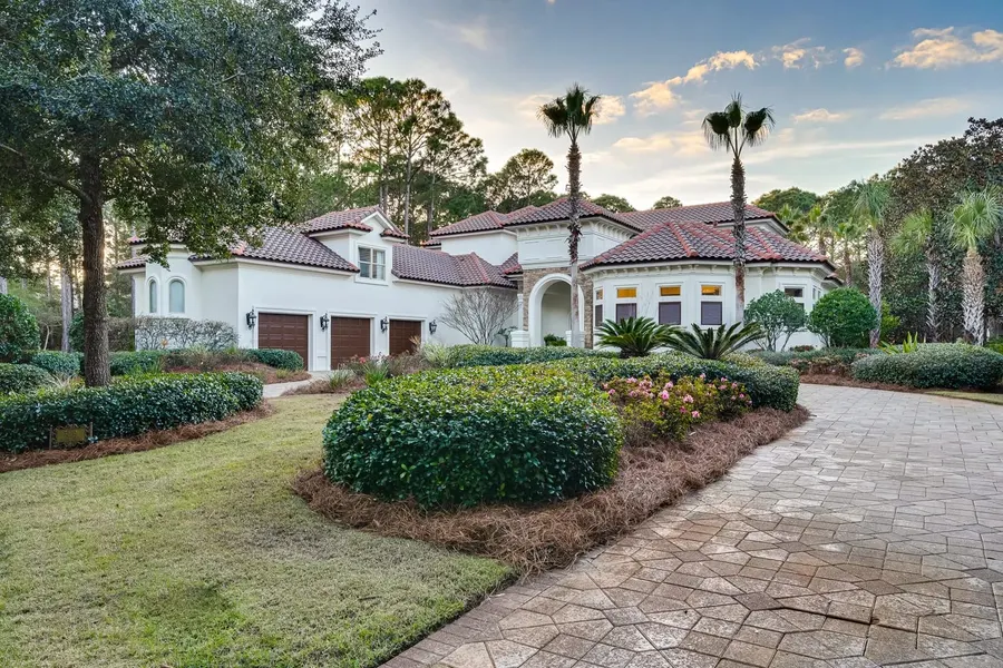 Mediterranean-style home with palms and lush landscaping at dusk