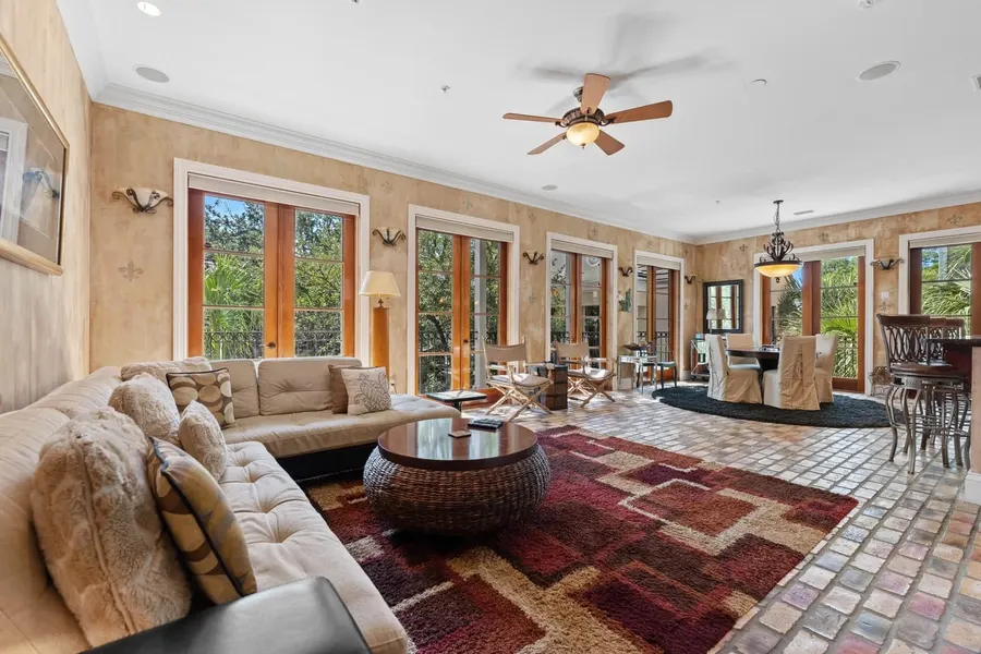 Tuscan-style living room with brick floors, french doors, and ceiling fan