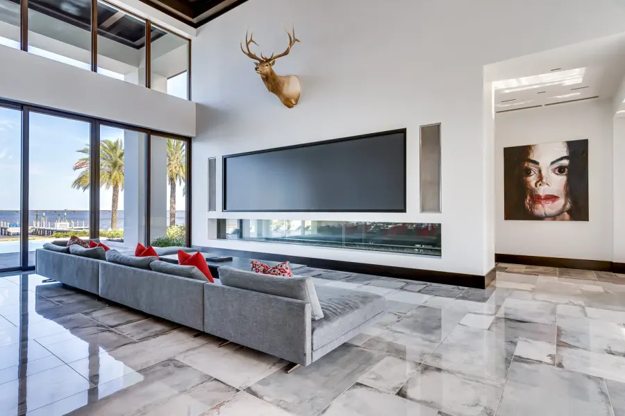 Modern great room with big-screen TV, marble floors, and waterfront palm views
