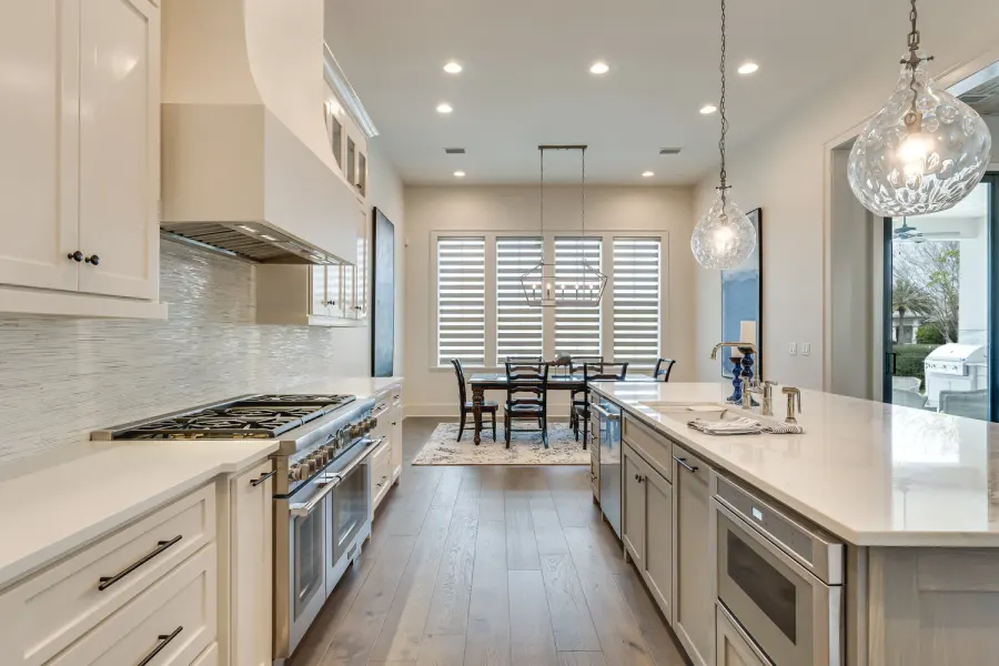 Bright white kitchen with glass pendant lights, island, and professional range
