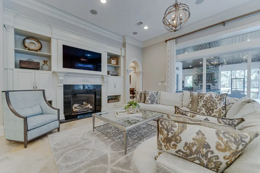 Elegant neutral living room with fireplace, built-ins, and orb chandelier