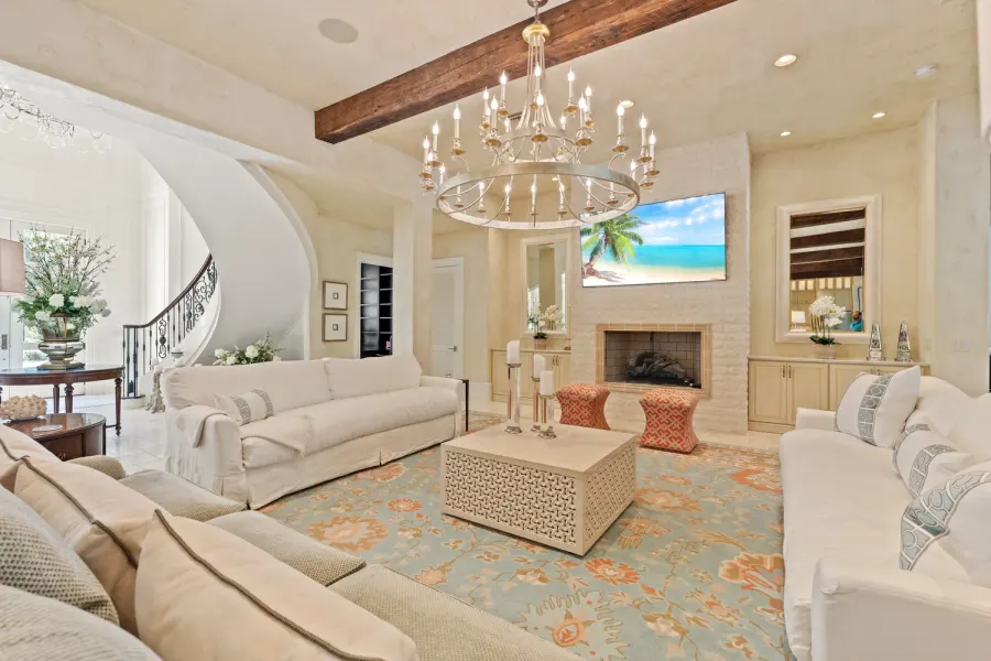 Luxury living room with candle chandelier, curved staircase, and fireplace