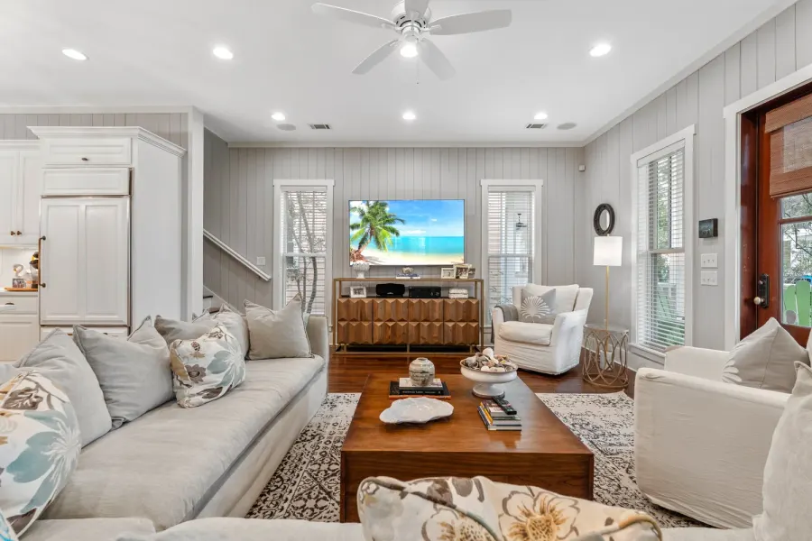 Coastal family room with shiplap walls, ceiling fan, and wood coffee table