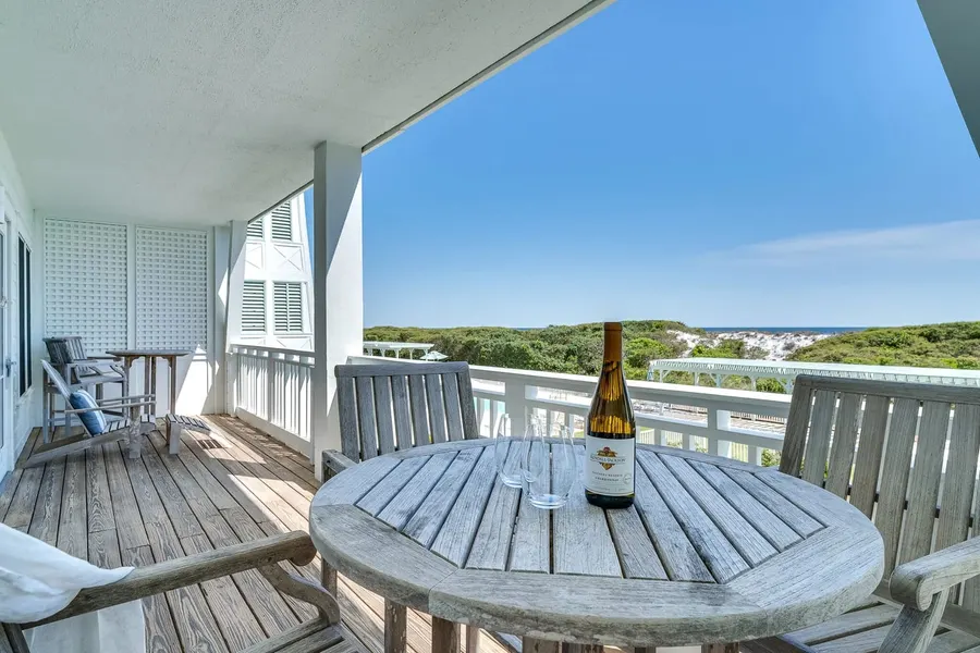 Beachside porch with wine on a round wood table overlooking gulf dunes
