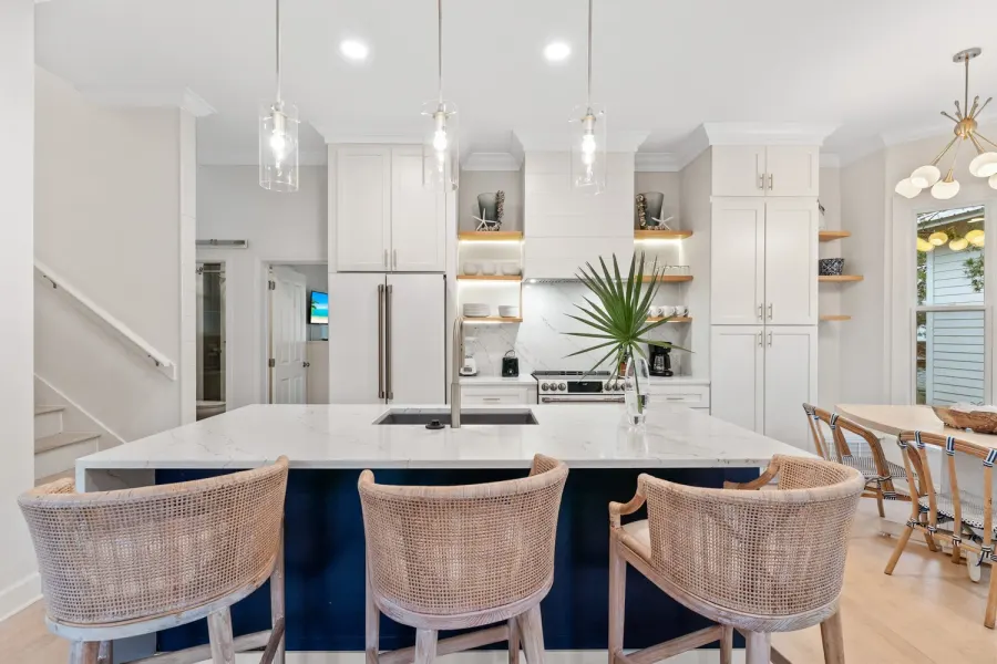 White kitchen with marble island and rattan barstools