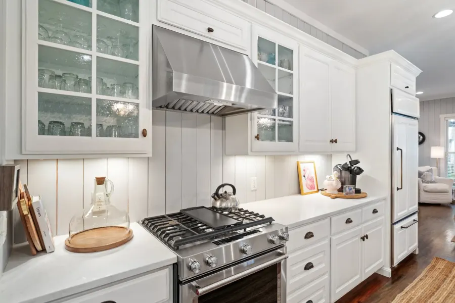Cottage kitchen with shiplap walls, glass cabinets and stainless range