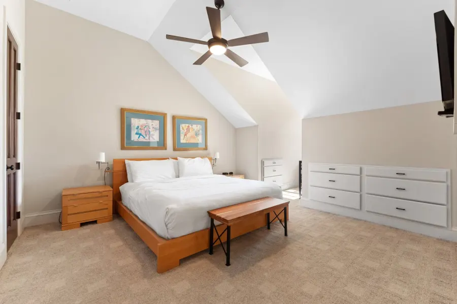Vaulted bedroom with king bed, ceiling fan and built-in dressers