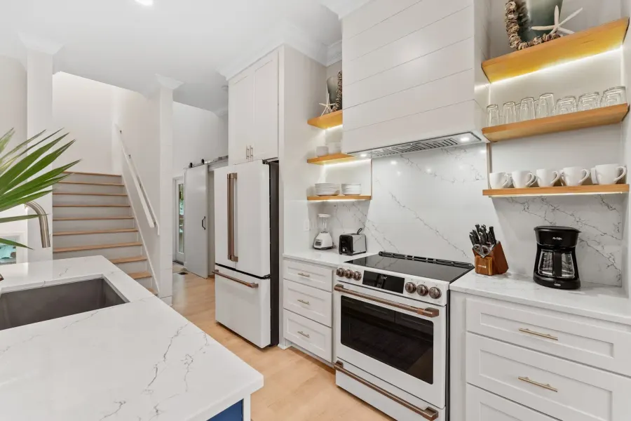 Coastal white kitchen with floating shelves and marble backsplash