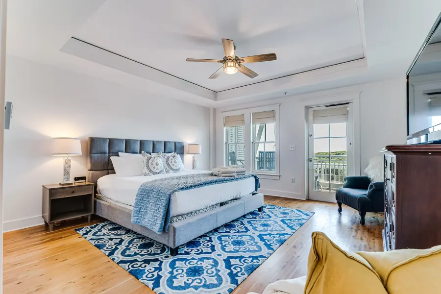 Master bedroom with tray ceiling, blue patterned rug, and balcony access
