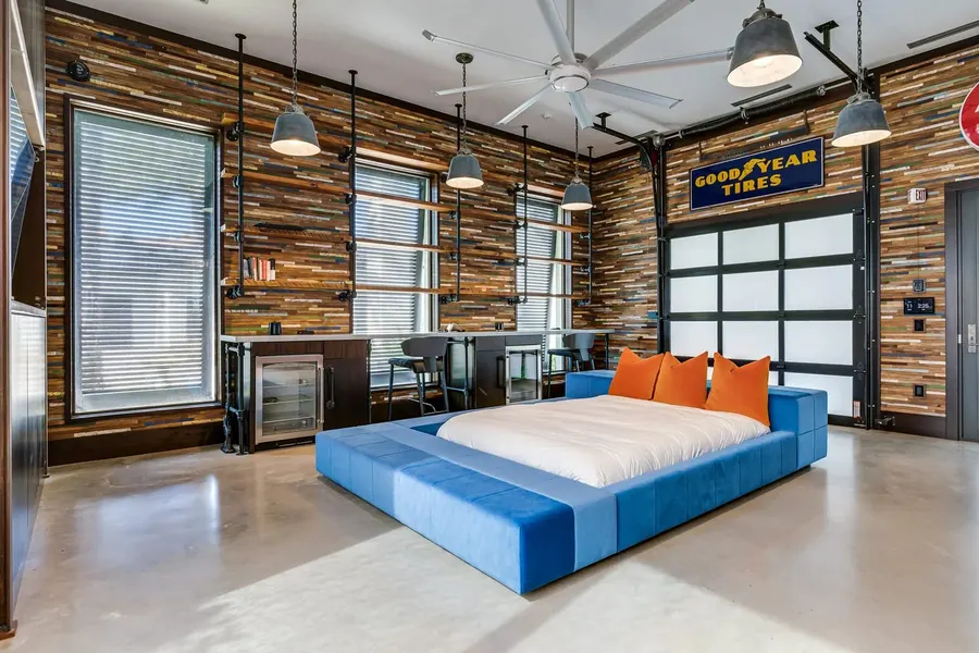 Industrial garage-style bunk room with reclaimed wood walls and blue platform bed