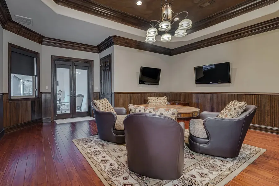 Traditional game room with leather swivel chairs, dual TVs, and wood wainscoting
