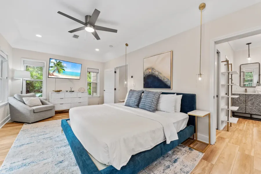Airy master bedroom with navy upholstered bed and en suite bath