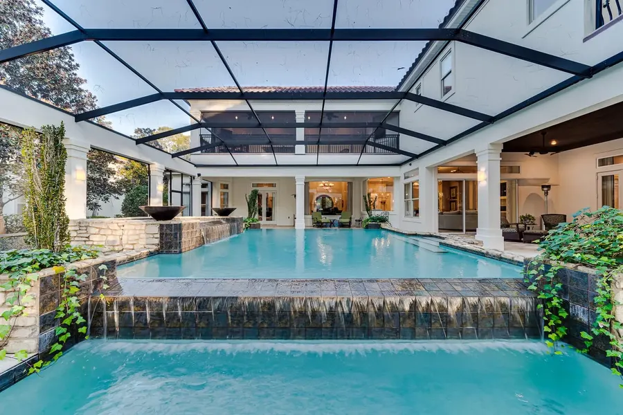Screened courtyard pool with waterfall spillways at a luxury Florida estate