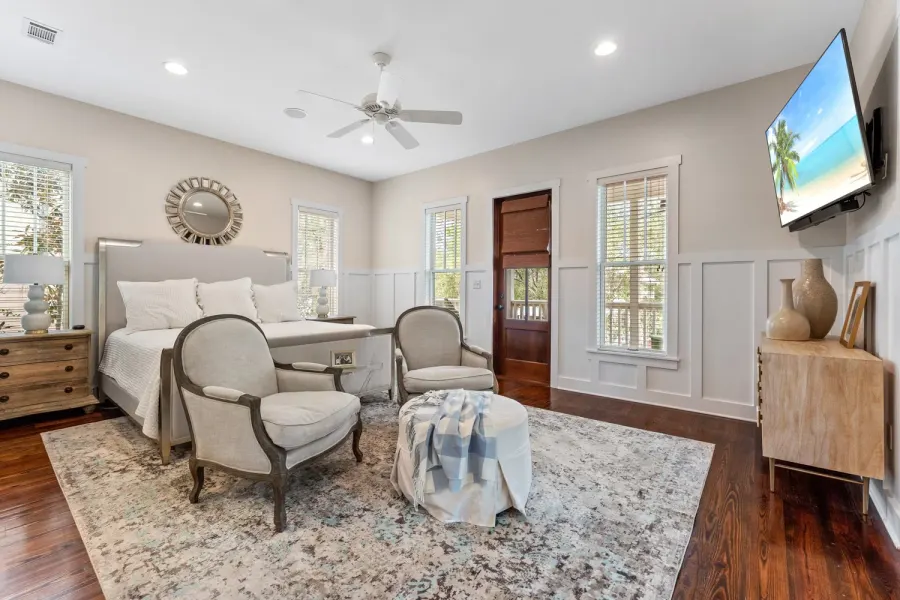 Coastal bedroom with upholstered king bed, sitting chairs, and wall-mounted TV