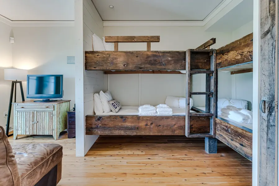 Bunk room with rustic reclaimed wood beds and folded white towels