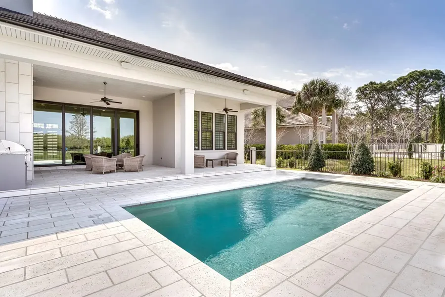 Backyard pool and covered lanai with wicker seating under Florida palms