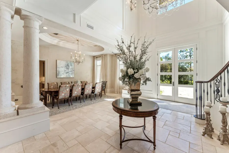 Grand two-story foyer with stone columns, round table, and floral centerpiece
