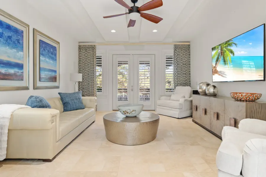 Bright living room with cream sofas, hammered metal coffee table, and beach art