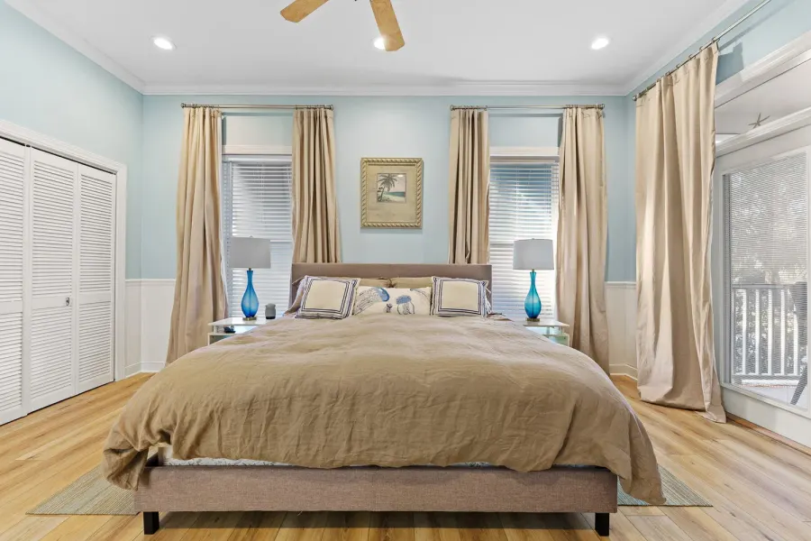 Light blue bedroom with king bed, tan linens, and flowing drapes