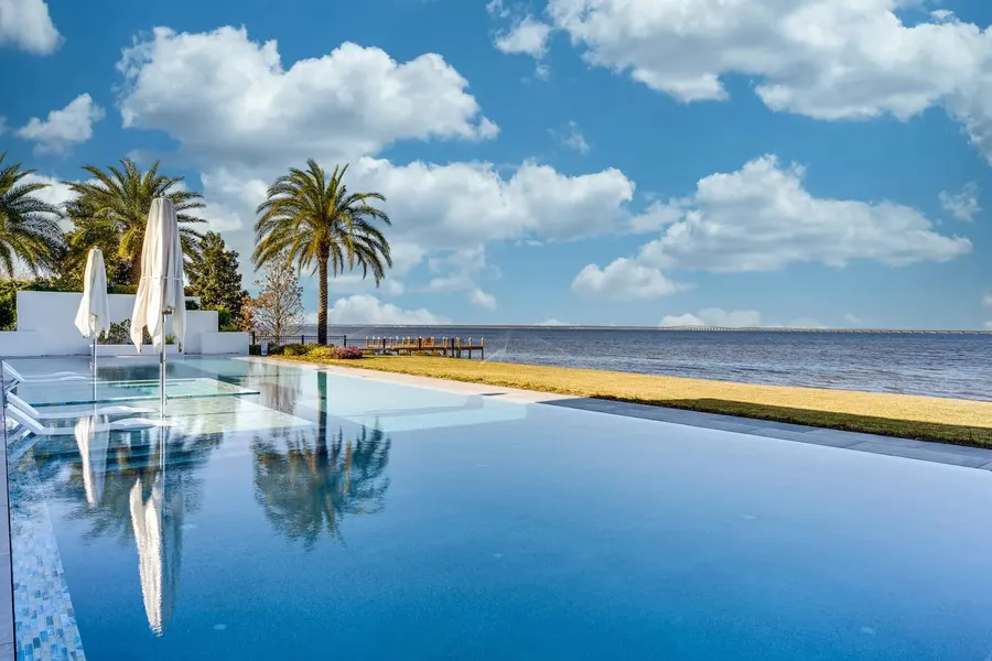 Infinity-edge pool with palm trees overlooking a wide Florida bay