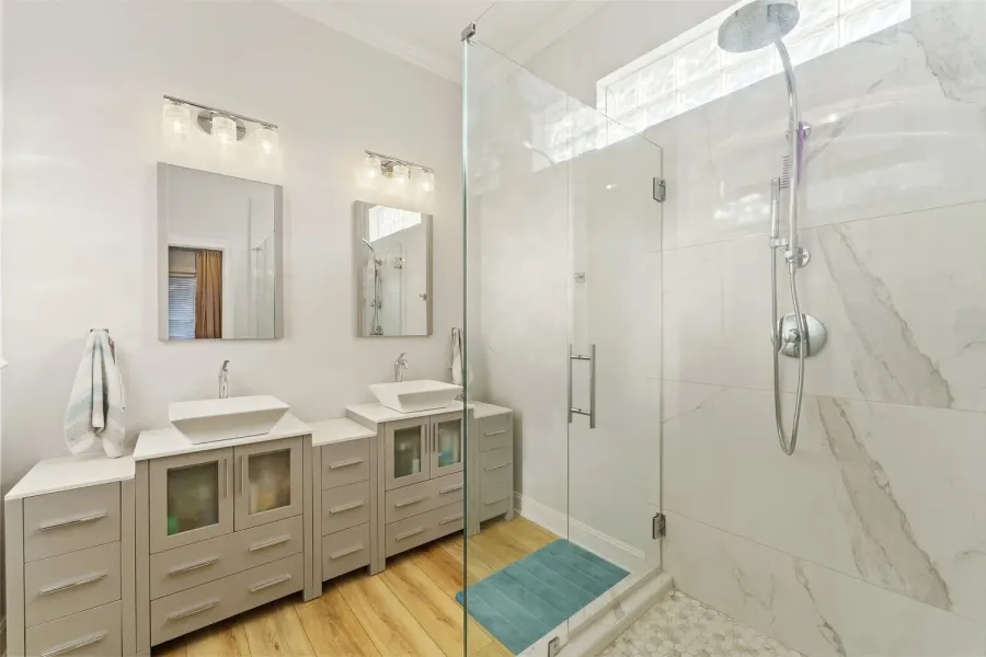 Bright bathroom with dual vessel sinks and glass walk-in shower