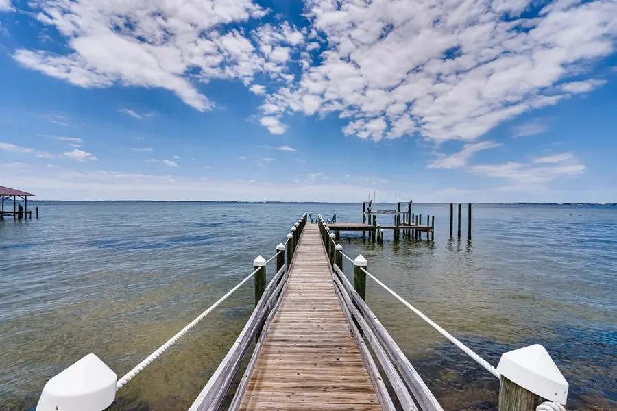 Private wooden dock stretching into calm bay waters under blue skies