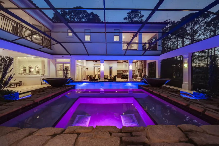 Screened lanai pool and spa glowing purple at twilight