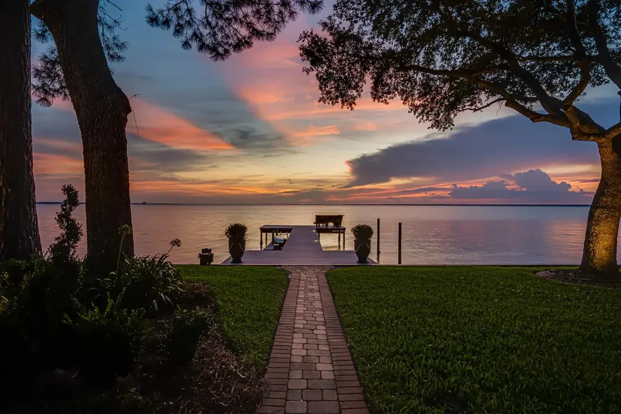 Brick path leading to a private dock under a vivid twilight sky